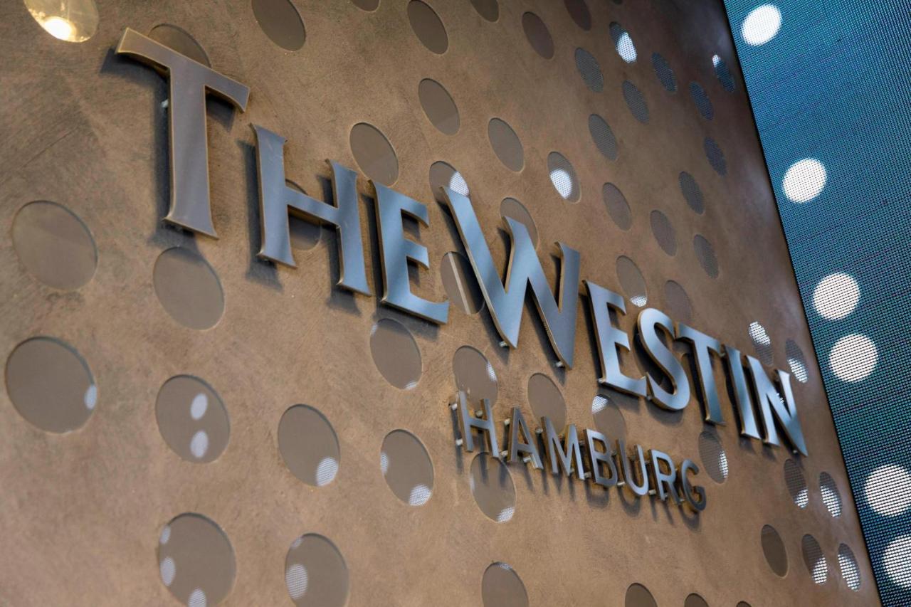 The Westin Hamburg Elbphilharmonie Hotel Екстериор снимка The image shows a decorative wall featuring the logo of "The Westin Hamburg." The logo is prominently displayed in a sleek, silver font. The background has a textured surface with circular patterns, adding a modern and elegant touch to the overall ap