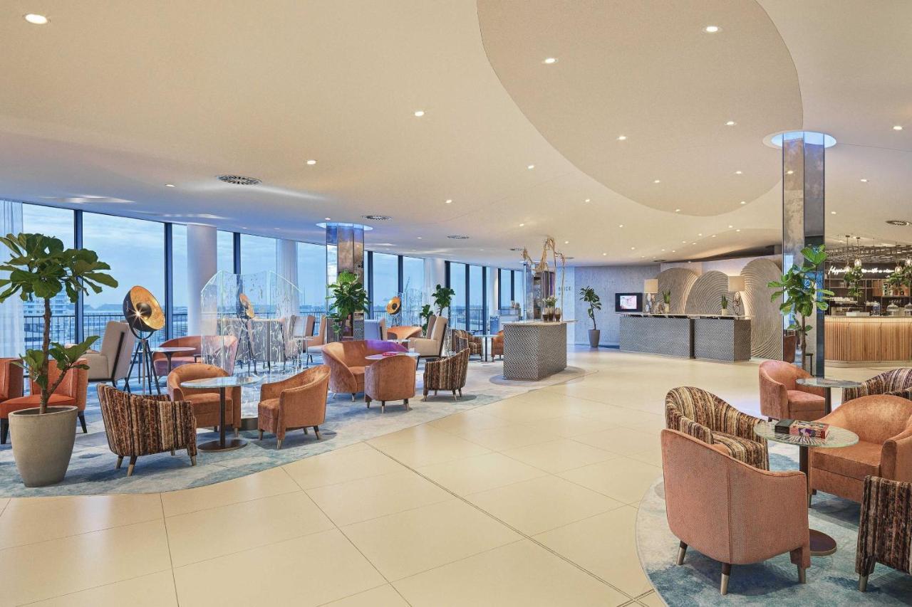 The Westin Hamburg Elbphilharmonie Hotel Екстериор снимка The image shows a modern, stylish interior, likely from a hotel or upscale lounge. The space features large windows that allow natural light to flood in, offering a view of the outside. There's a mix of comfortable seating arrangements, including sev