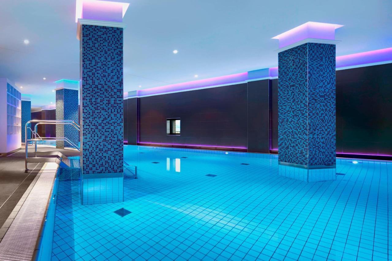 The Westin Hamburg Elbphilharmonie Hotel Екстериор снимка The image shows a swimming pool area that features a modern, upscale design. The pool has bright blue tiles reflecting the water, creating a vibrant atmosphere. There are two columns dressed in a similar blue tile pattern, and the walls are adorned w