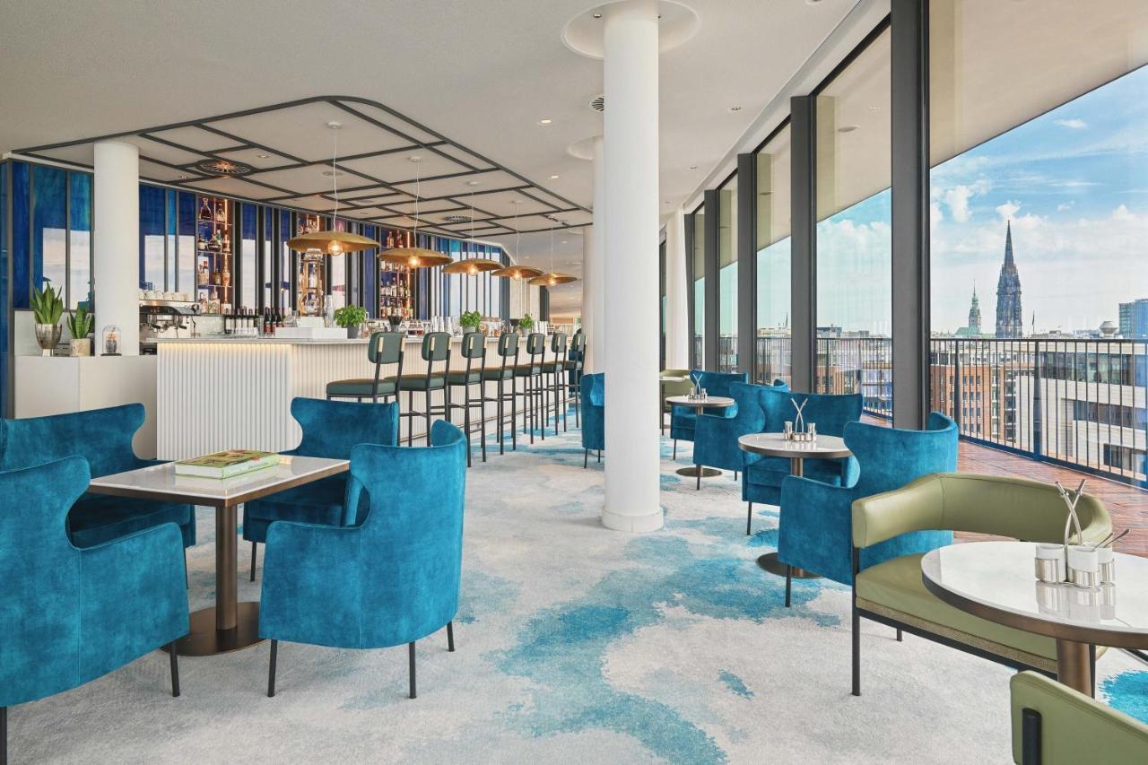 The Westin Hamburg Elbphilharmonie Hotel Екстериор снимка The image shows a stylish and modern restaurant interior. There are several tables with blue and green chairs, creating a cozy atmosphere. The flooring features a light carpet with abstract patterns. Large windows provide plenty of natural light and 