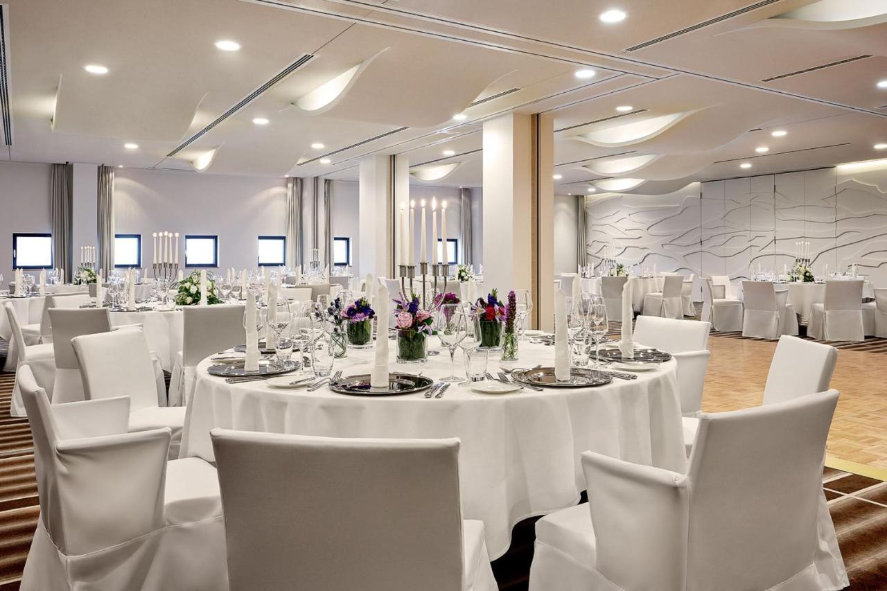 The Westin Hamburg Elbphilharmonie Hotel Екстериор снимка The photo depicts a modern banquet or event hall setup. It features round tables covered with white tablecloths, each set with elegant dishware and glassware. The tables are adorned with floral centerpieces, adding a touch of color, and there are tal