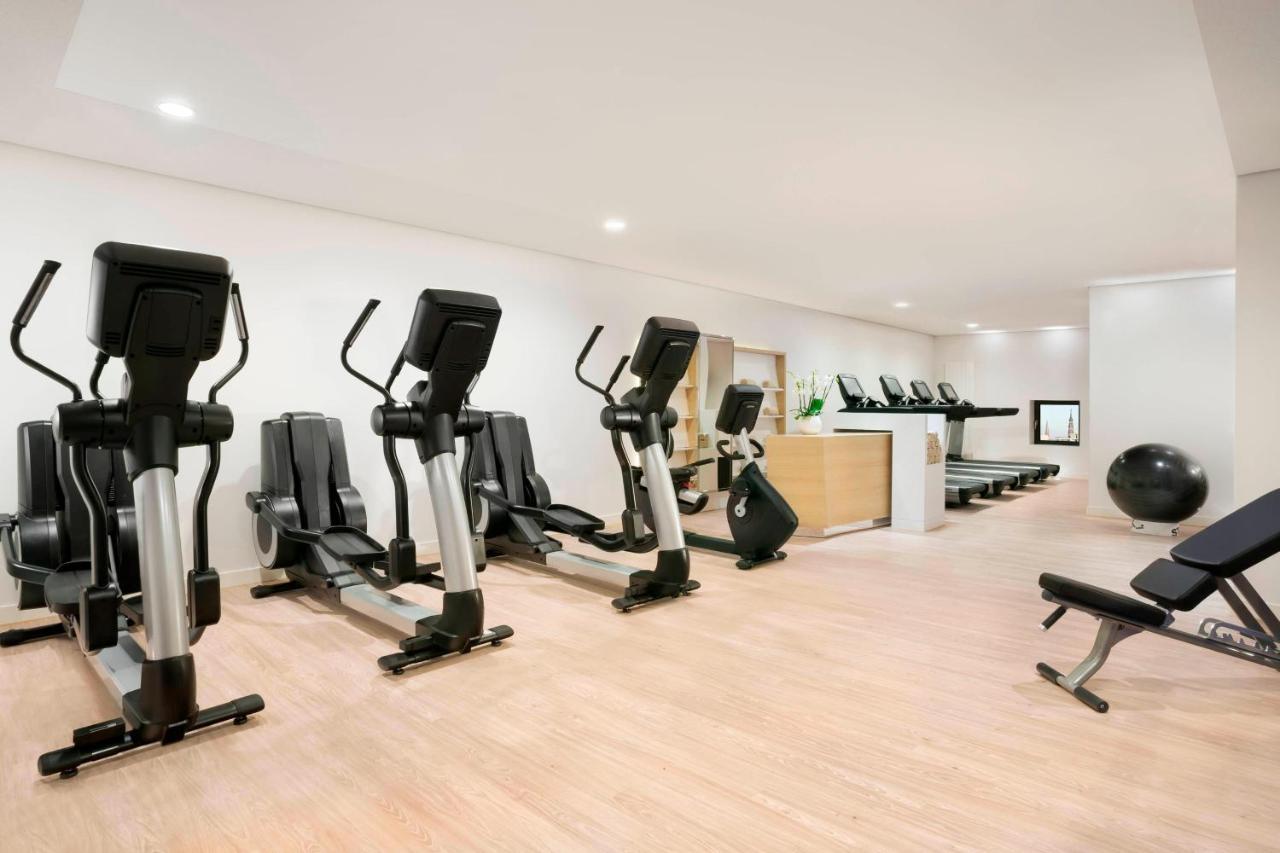 The Westin Hamburg Elbphilharmonie Hotel Екстериор снимка The photo shows a fitness room with several pieces of exercise equipment. On the left side, there are multiple elliptical machines arranged in a row. In the center, there is a stationary bike. A workout bench is positioned nearby, and a large exercis