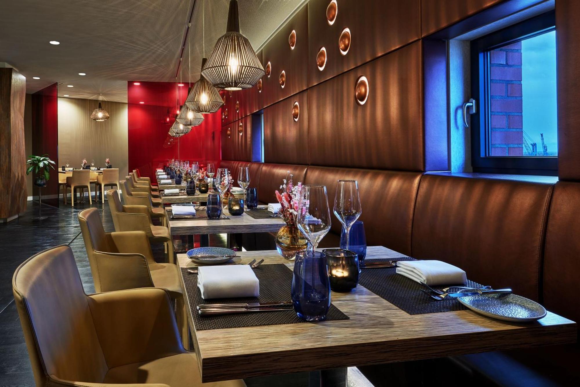 The Westin Hamburg Elbphilharmonie Hotel Екстериор снимка The photo shows a modern restaurant interior. It features a series of wooden tables set for dining, each equipped with white napkins and utensils. The seating consists of comfortable leather chairs. The walls are decorated with a combination of warm 
