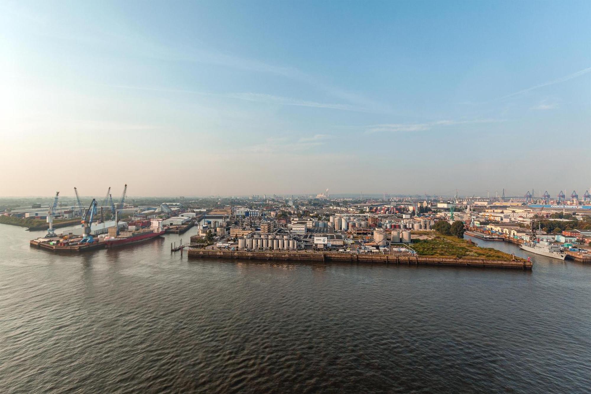 The Westin Hamburg Elbphilharmonie Hotel Екстериор снимка The photo shows a coastal area with a large body of water in the foreground. To the left, there are industrial structures like cranes and cargo ships, indicating an active port or shipping area. In the background, there are various buildings, which a